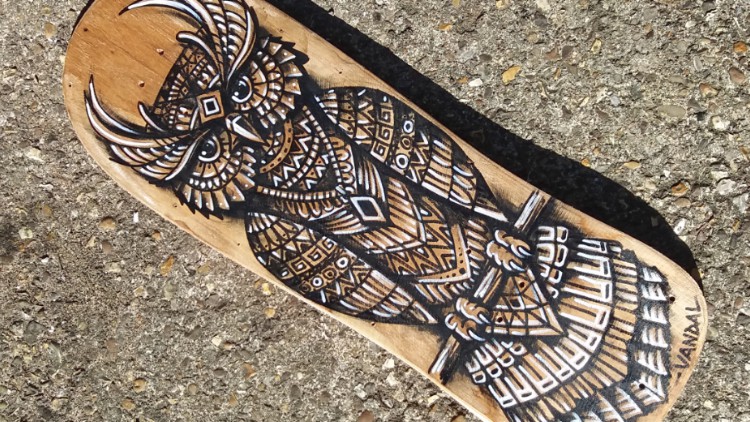 Drawing an owl on an old upcycled skateboard